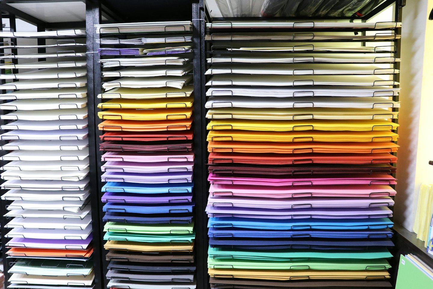 Pilas de papel de colores organizadas en estanterías altas de metal.